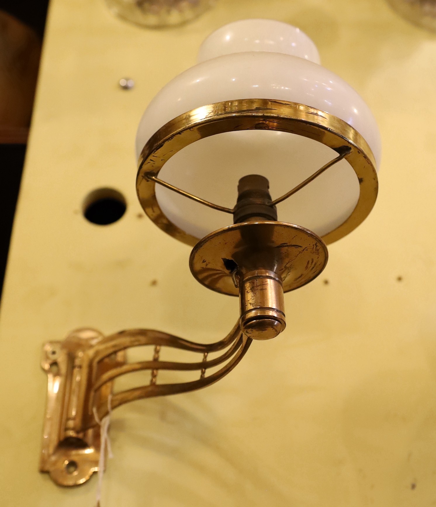 A pair of late Victorian brass swivelling wall lights with opaque glass shades, height 25cm. depth 25cm